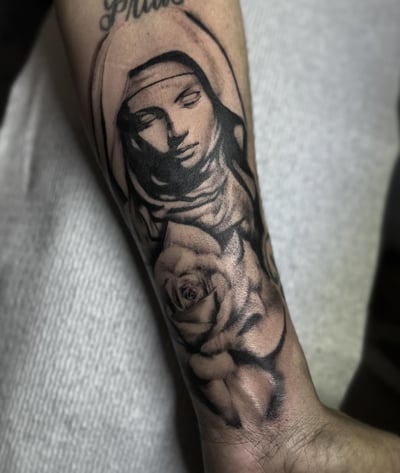 A black and grey tattoo of a woman's portrait with a rose on the forearm, featuring detailed shading and dark tones — by Maddie Ramirez, los angeles