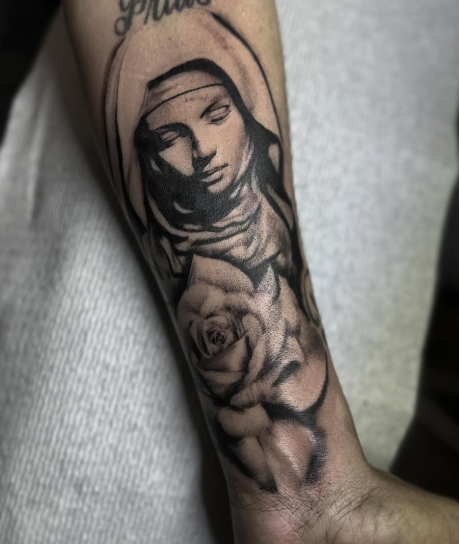 A black and grey tattoo of a woman's portrait with a rose on the forearm, featuring detailed shading and dark tones — by Maddie Ramirez, los angeles