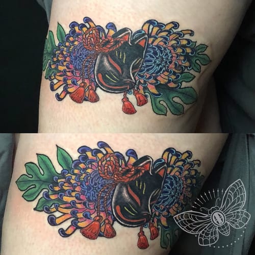 A colorful Japanese kitsune mask with vibrant flowers on the arm, featuring bold and ornate design elements — by Sandra Price, los angeles