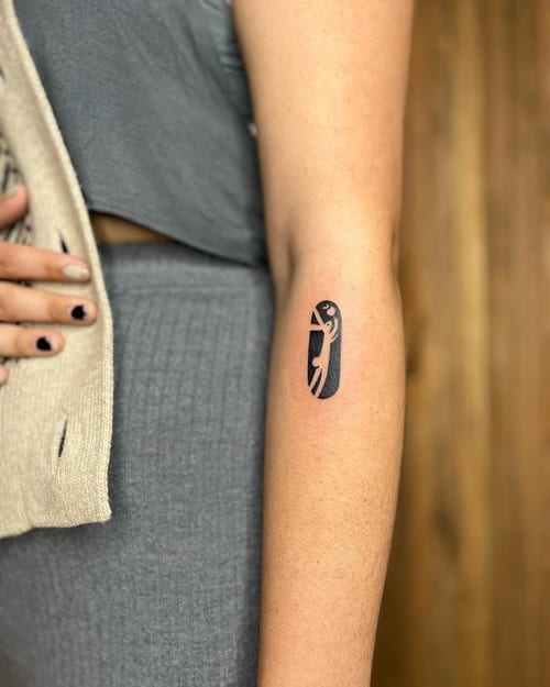 A minimalist blackwork tattoo of an abstract figure on the forearm, featuring simple lines and shapes — by Dylan Aiello, los angeles