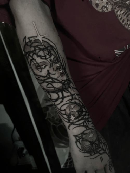 A black and grey abstract tattoo on the forearm featuring a face intertwined with spider web patterns and linework — by tyler_whitlock, los angeles