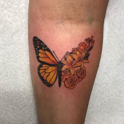 A vibrant color tattoo of a butterfly and flowers on the forearm, featuring realistic details and delicate shading — by Sandra Price, los angeles