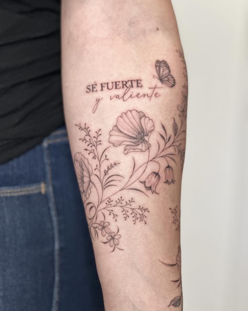 A delicate black and grey floral design with script lettering and a butterfly on the forearm — by Melanie Benoit, los angeles