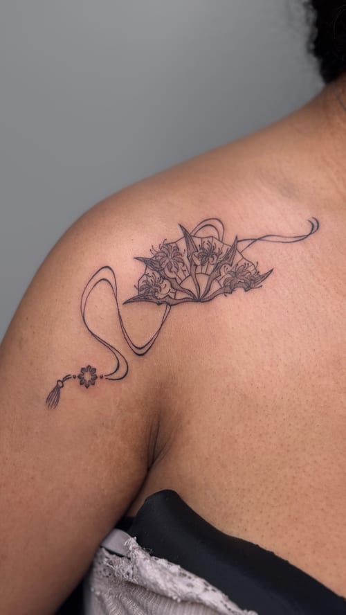 A delicate black and grey fine line floral tattoo on the shoulder, featuring intricate flower designs with flowing lines — by NJ TATTOOZ, los angeles