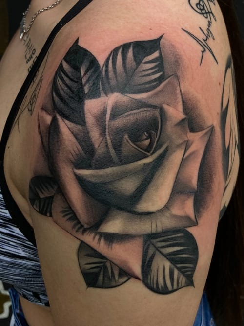A realistic black and grey rose tattoo on the shoulder, featuring detailed shading and depth — by Josue Bravo, los angeles