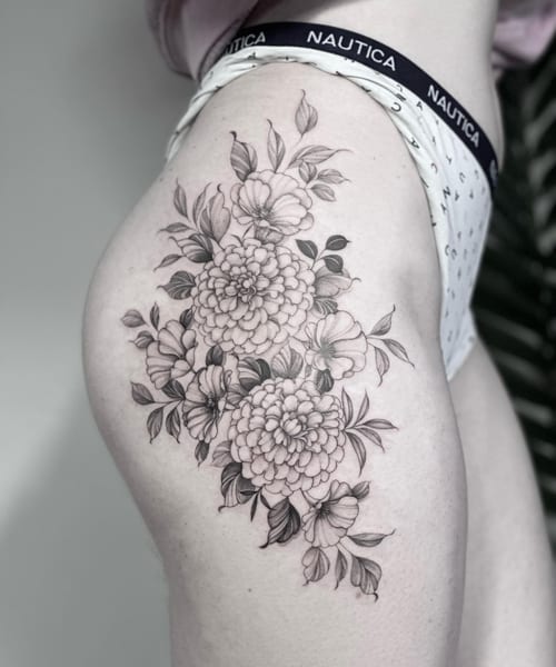 A delicate black and grey floral bouquet tattoo on the thigh, featuring detailed flowers and leaves — by Melanie Benoit, los angeles