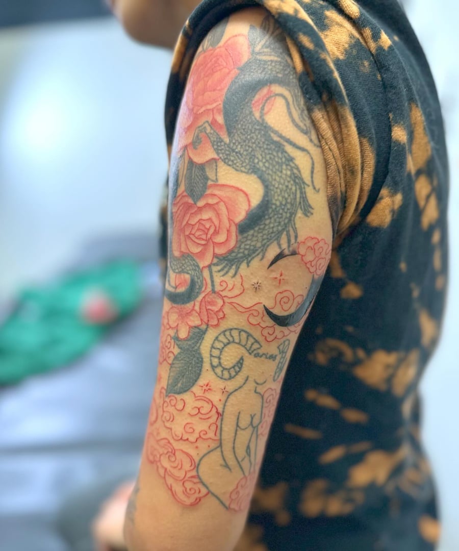 A colorful Japanese style tattoo of a dragon with flowers and clouds on the upper arm — by Maddie Ramirez, los angeles
