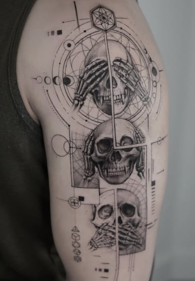 A black and grey geometric tattoo featuring three skulls with hands covering their eyes, ears, and mouth, surrounded by intricate geometric patterns on the upper arm — by Jian Liang, los angeles