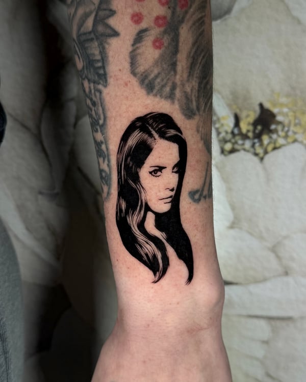 A black and grey portrait of a woman on the forearm, featuring bold blackwork style with detailed shading — by emily, rahway