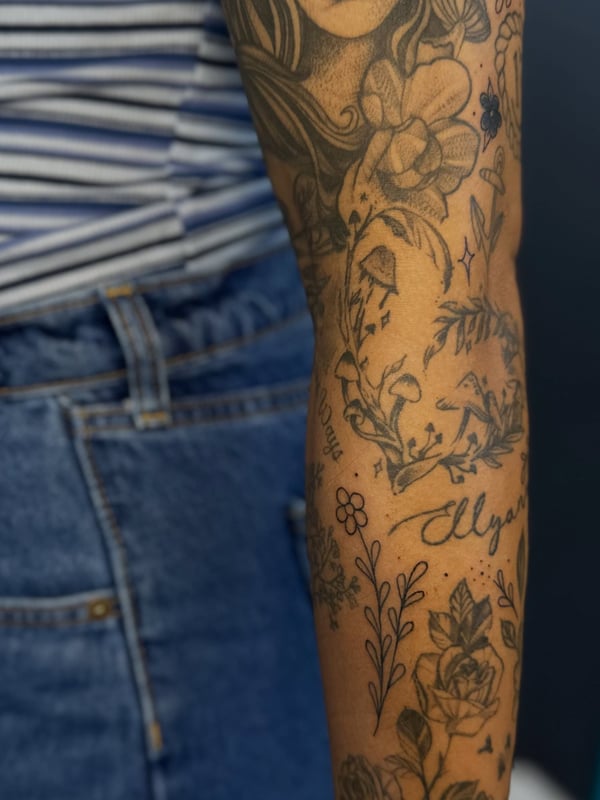 A black and grey floral and script filler tattoo on the forearm in an illustrative style — by Maddie Ramirez, palm desert, ca