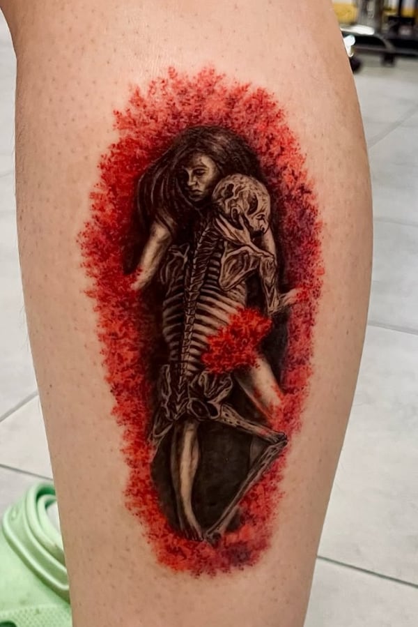 A mixed color realism tattoo on the leg depicting a woman embracing a skeleton, surrounded by a red textured background — by zitronxus, los angeles