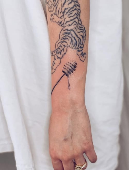 A minimalist black and grey fine line tattoo of a tiger on the forearm, featuring simple and clean lines — by Level tattoo, los angeles