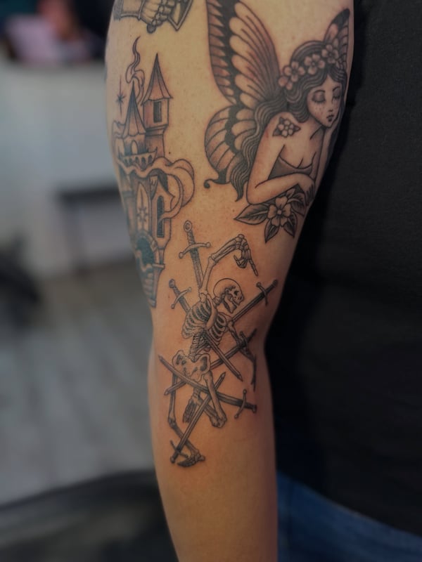 A traditional black and grey skeleton with swords on the upper arm — by Maddie Ramirez, palm desert, ca