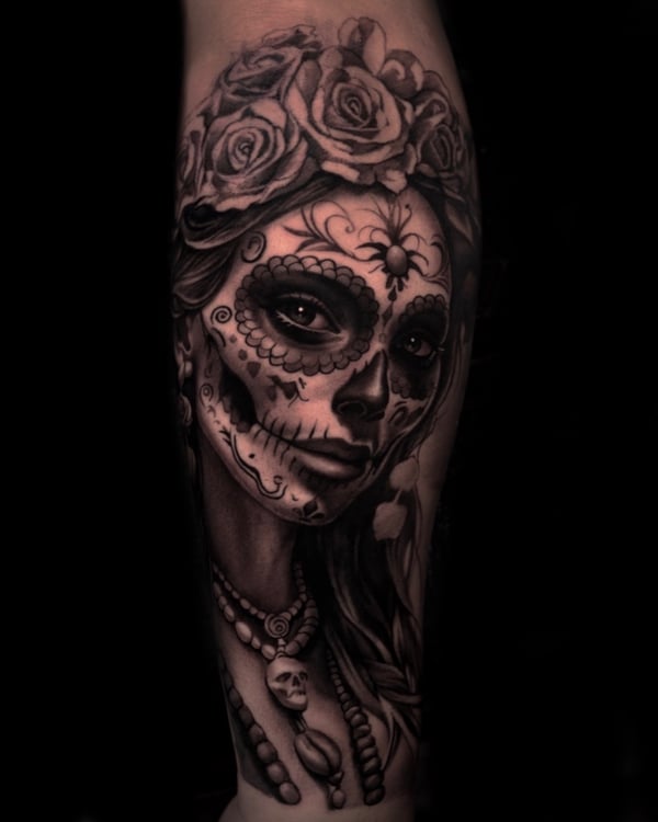 A detailed black and grey sugar skull woman portrait on the forearm, featuring roses and intricate facial designs — by Vladimir Kozachenko, los angeles