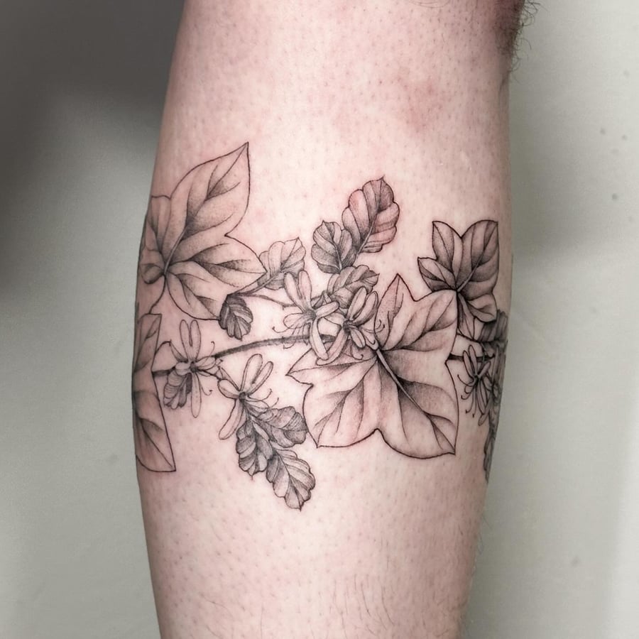 A delicate black and grey botanical tattoo featuring leaves and flowers on the forearm — by Melanie Benoit, los angeles