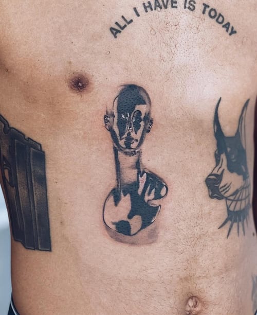 An abstract black and grey tattoo of a stylized face on the stomach, featuring bold black shapes and minimal detail — by Level tattoo, los angeles