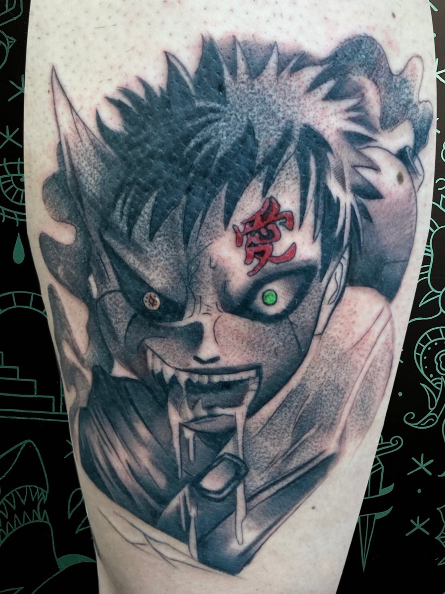 An anime-inspired black and grey tattoo on the leg, featuring a character's intense face with a glowing green eye and red symbol on the forehead — by Josue Bravo, los angeles