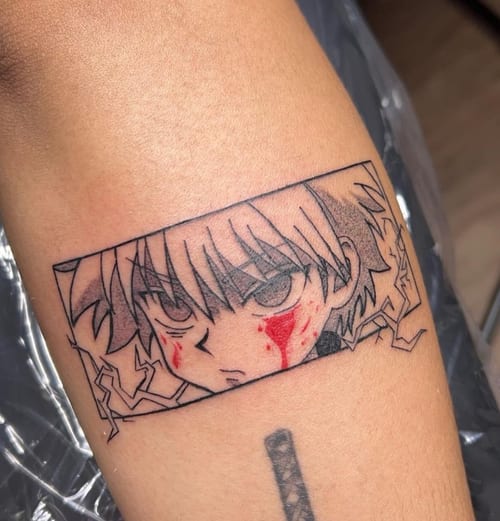 A mixed color and black linework anime-style tattoo of a character's face on the arm, featuring sharp lines and red accents — by NJ TATTOOZ, los angeles