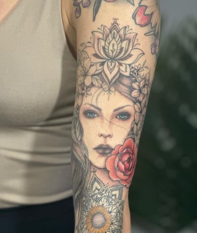 A neo-traditional woman's portrait with floral elements on the arm, featuring a mix of color and black and grey ink — by Melanie Benoit, los angeles