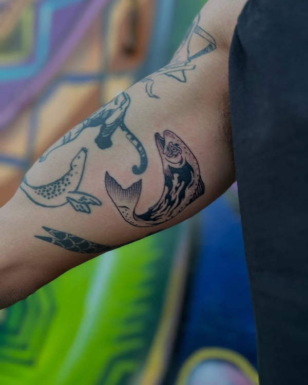 A black and grey linework fish tattoo on the arm with a graphic style — by Dylan Aiello, los angeles