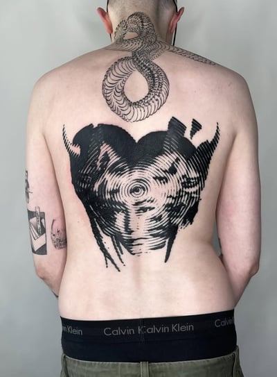 A black and grey abstract blackwork tattoo on the back, featuring a snake design extending from the neck and an abstract pattern resembling a heart or vortex — by Level tattoo, los angeles