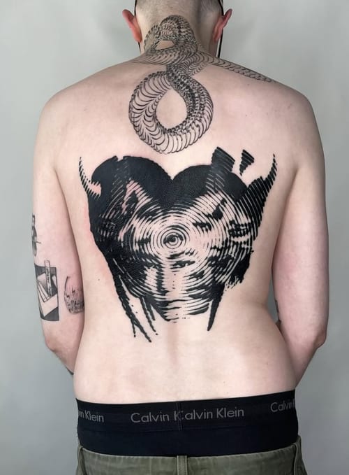 A black and grey abstract blackwork tattoo on the back, featuring a snake design extending from the neck and an abstract pattern resembling a heart or vortex — by Level tattoo, los angeles