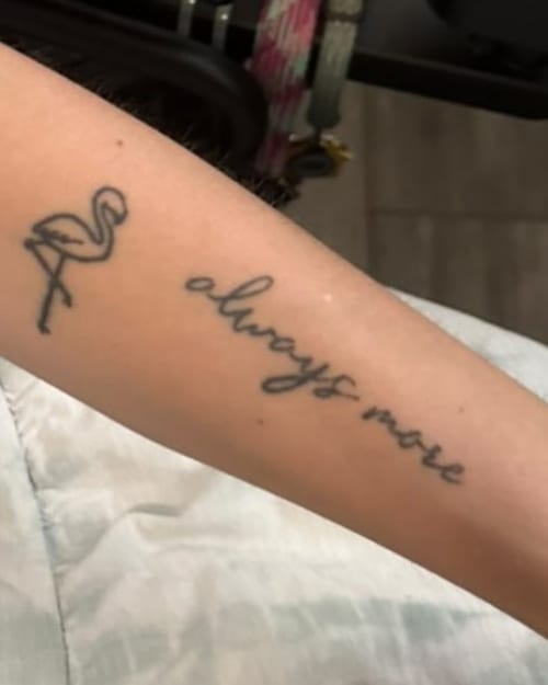 A minimalist black ink flamingo and script tattoo on the forearm, featuring simple linework — by Melanie Benoit, los angeles