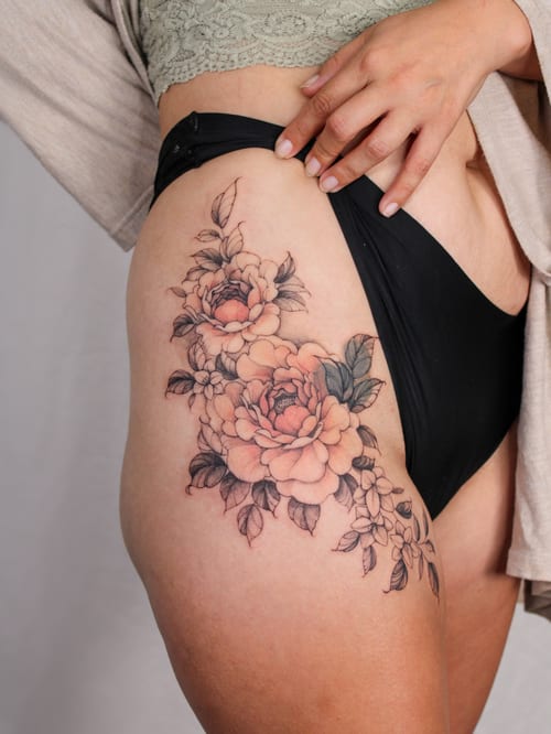 A delicate floral bouquet tattoo on the thigh with fine line work and soft colors — by Melanie Benoit, los angeles