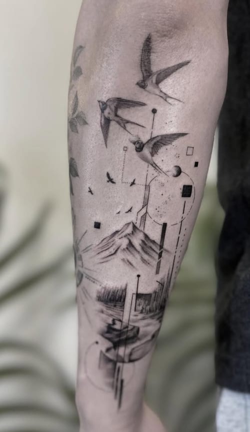 A black and grey geometric tattoo on the forearm featuring birds flying over a mountain with abstract elements and fine line details — by Jian Liang, los angeles