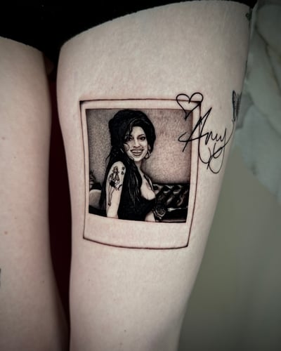 A black and grey realism portrait of a woman in a polaroid frame on the thigh, with fine detail and shading — by emily, los angeles