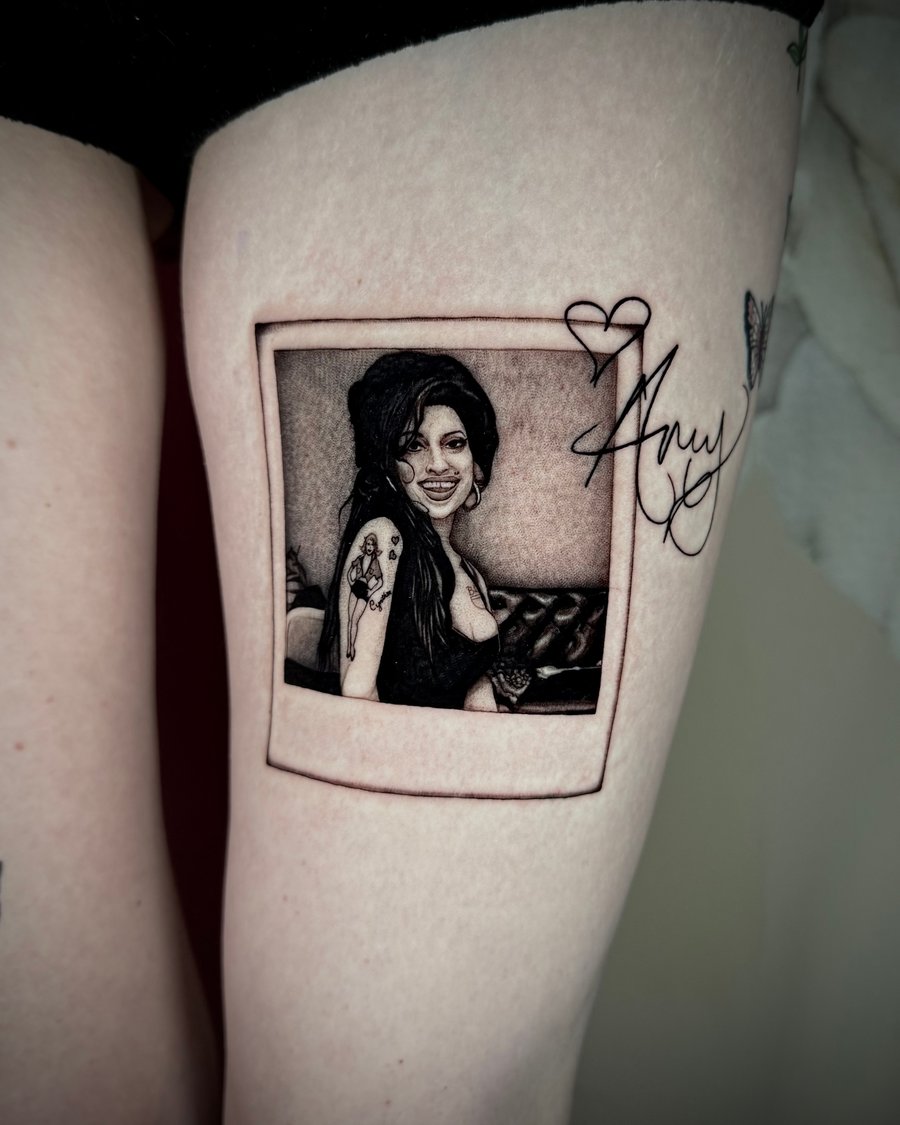 A black and grey realism portrait of a woman in a polaroid frame on the thigh, with fine detail and shading — by emily, los angeles