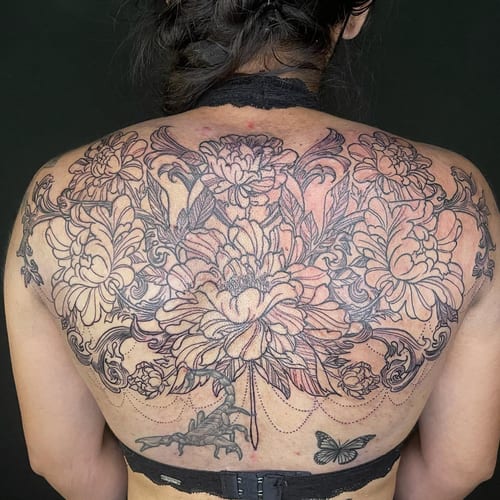 A detailed black and grey floral arrangement on the back featuring a scorpion and butterfly, with ornate linework — by Sandra Price, los angeles