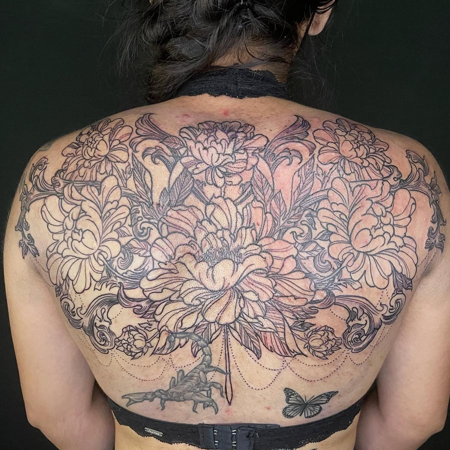 A detailed black and grey floral arrangement on the back featuring a scorpion and butterfly, with ornate linework — by Sandra Price, los angeles