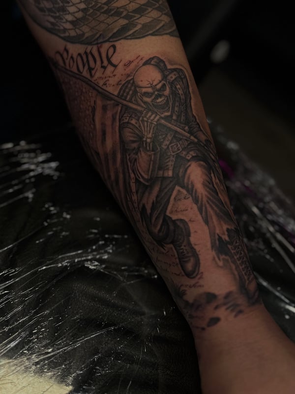 A detailed black and grey tattoo of Eddie the Trooper from Iron Maiden on the forearm — by Maddie Ramirez, palm desert, ca