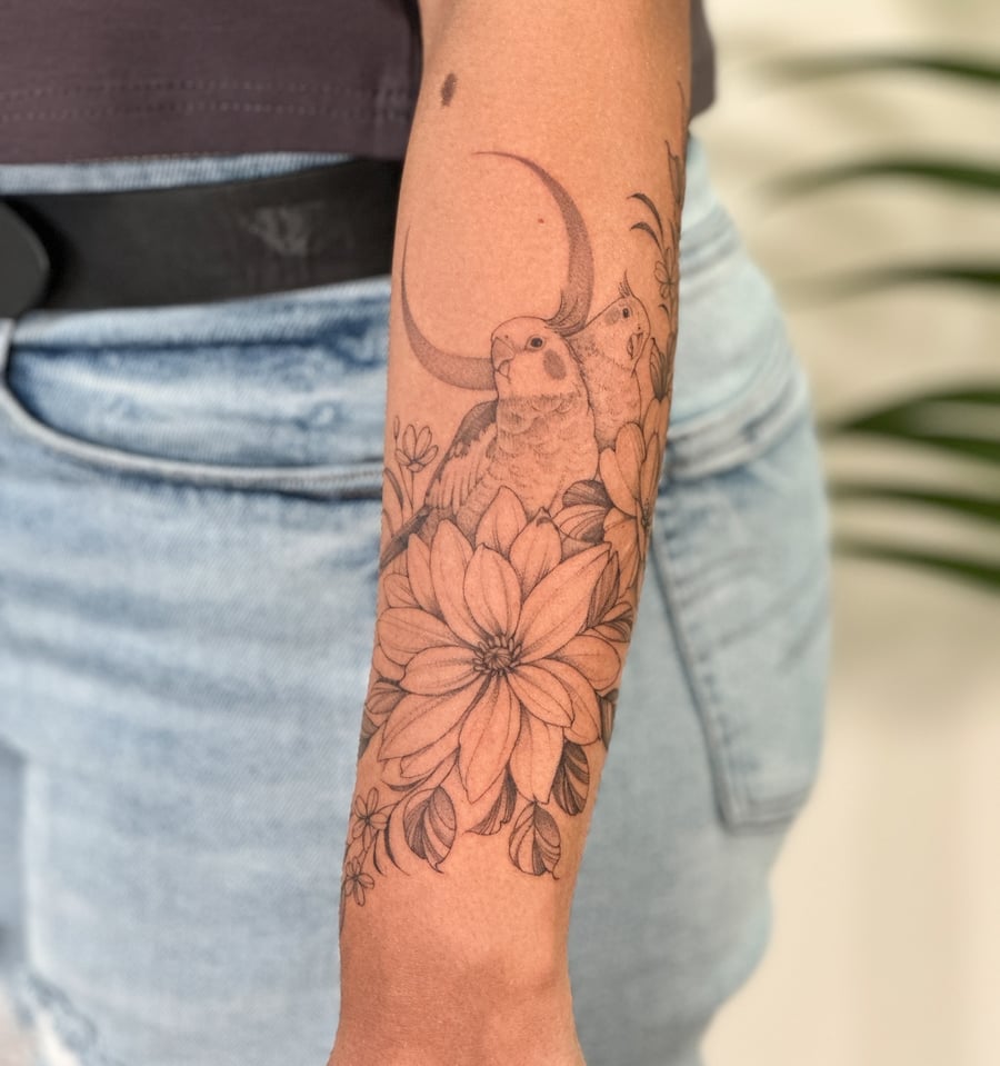 A delicate black and grey tattoo of birds and flowers on the forearm, featuring fine line work and a crescent moon — by Melanie Benoit, los angeles