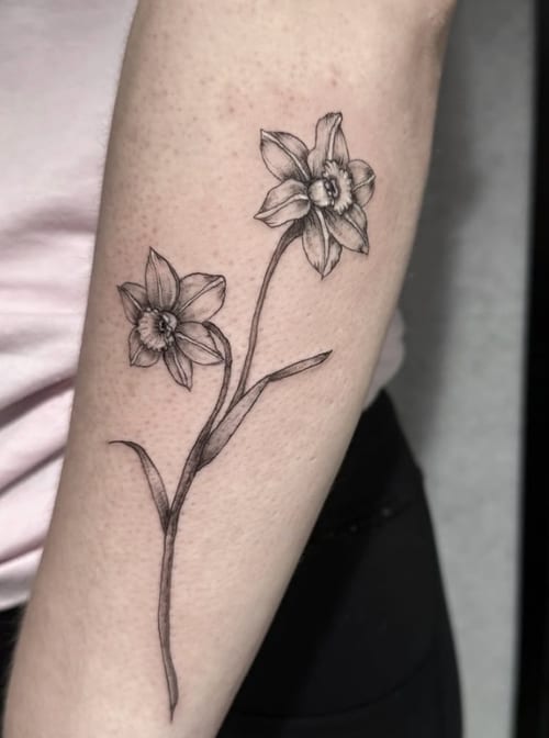 A fine line black and grey tattoo of two flowers on the forearm, featuring delicate linework and shading — by Shelby Bianco, los angeles