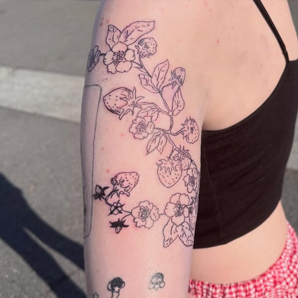 fine line tattoo of a strawberry vine with blossoms and small bees running down the upper arm by Hannah, a tattoo artist in fountain valley, california