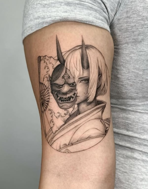 A black and grey illustrative tattoo on the upper arm depicting a woman with a traditional Japanese mask, featuring fine line work and detailed shading — by otaybeatdown, orange, ca