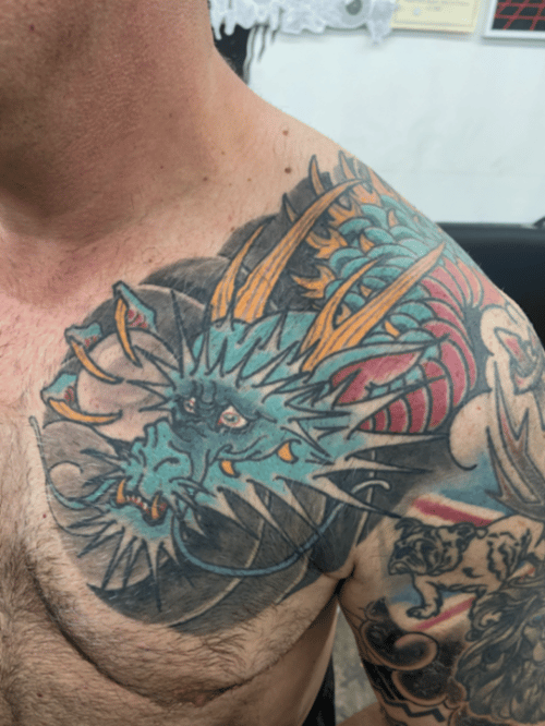 A vibrant Japanese-style dragon tattoo on the shoulder, featuring bold colors and dynamic lines — by tyler_whitlock, los angeles