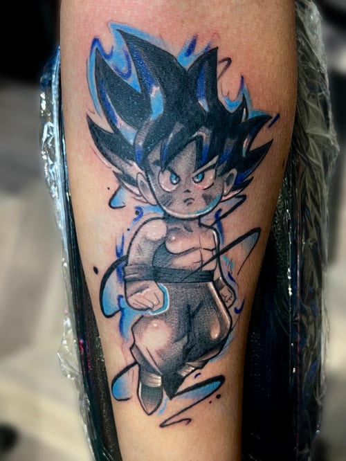 An illustrative anime character tattoo on the calf, featuring bold outlines and a mix of black and blue colors — by Josue Bravo, los angeles