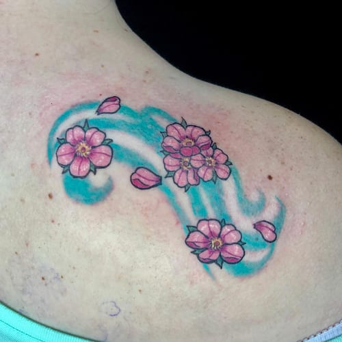 A colorful tattoo of cherry blossoms and a wave on the back, featuring a Japanese style with delicate pink flowers and blue water — by Sandra Price, los angeles