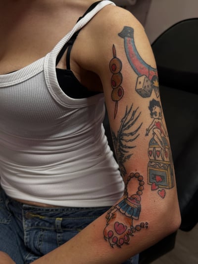 A colorful traditional sleeve tattoo featuring dice, hearts, and a woman on the full sleeve — by Maddie Ramirez, los angeles