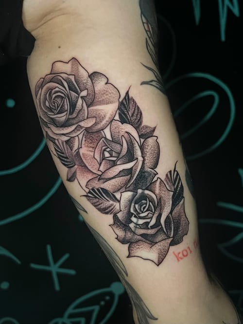 A black and grey tattoo of three roses on the forearm, featuring detailed dot shading and bold outlines — by Josue Bravo, los angeles