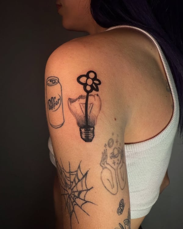 A minimalist blackwork tattoo of a flower growing inside a light bulb on the upper arm — by zealous, los angeles
