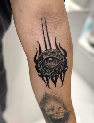 A black and grey ornamental tattoo of an eye with intricate patterns and flame-like elements on the inner arm — by otaybeatdown, los angeles