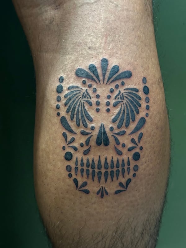 A bold blackwork ornamental skull tattoo on the calf with graphic elements and symmetrical design — by Humilde tattoos, los angeles
