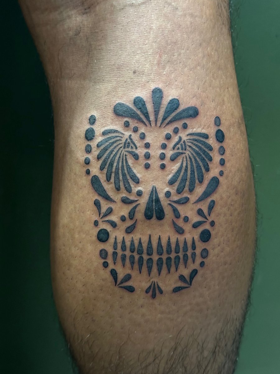 A bold blackwork ornamental skull tattoo on the calf with graphic elements and symmetrical design — by Humilde tattoos, los angeles