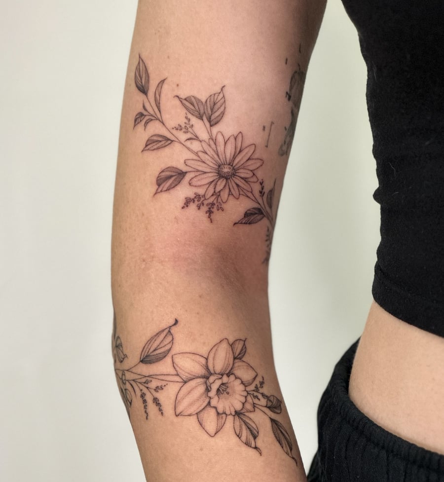A delicate black and grey fine line floral tattoo on the arm, featuring detailed flowers and leaves — by Melanie Benoit, los angeles