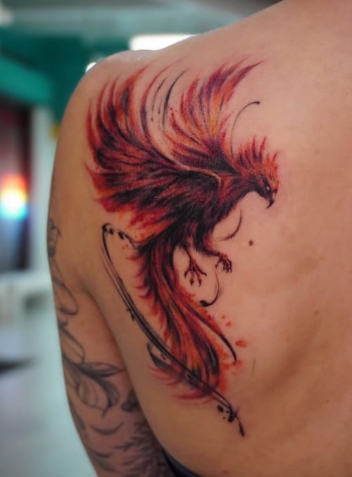 A vibrant watercolor tattoo of a phoenix on the shoulder, featuring dynamic red and orange hues with an illustrative style — by Jian Liang, los angeles