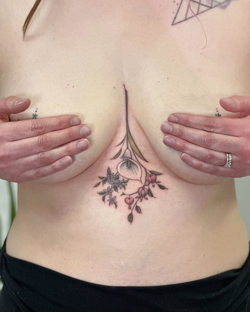 A delicate floral arrangement tattoo in color on the sternum, featuring fine line botanical elements — by Melanie Benoit, los angeles